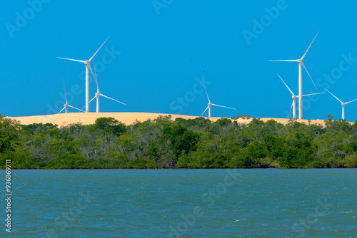VIEW OF THE JAGUARIBE RIVER IN THE MUNICIPALITY OF FORTIM ON THE EAST COAST OF THE STATE OF CEARÁ WITH A RENEWABLE ENERGY WIND FARM UNDER THE SAND DUNES IN THE BACKGROUND.
