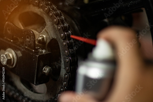 Photos Close-up of a bicycle mechanic cleaning a chain with chain lube spray