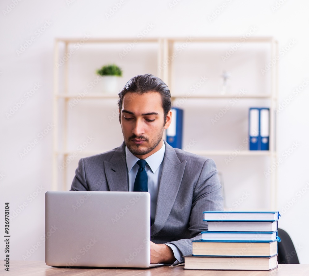 Young male businessman reading books at workplace Young male businessman reading books at workplace