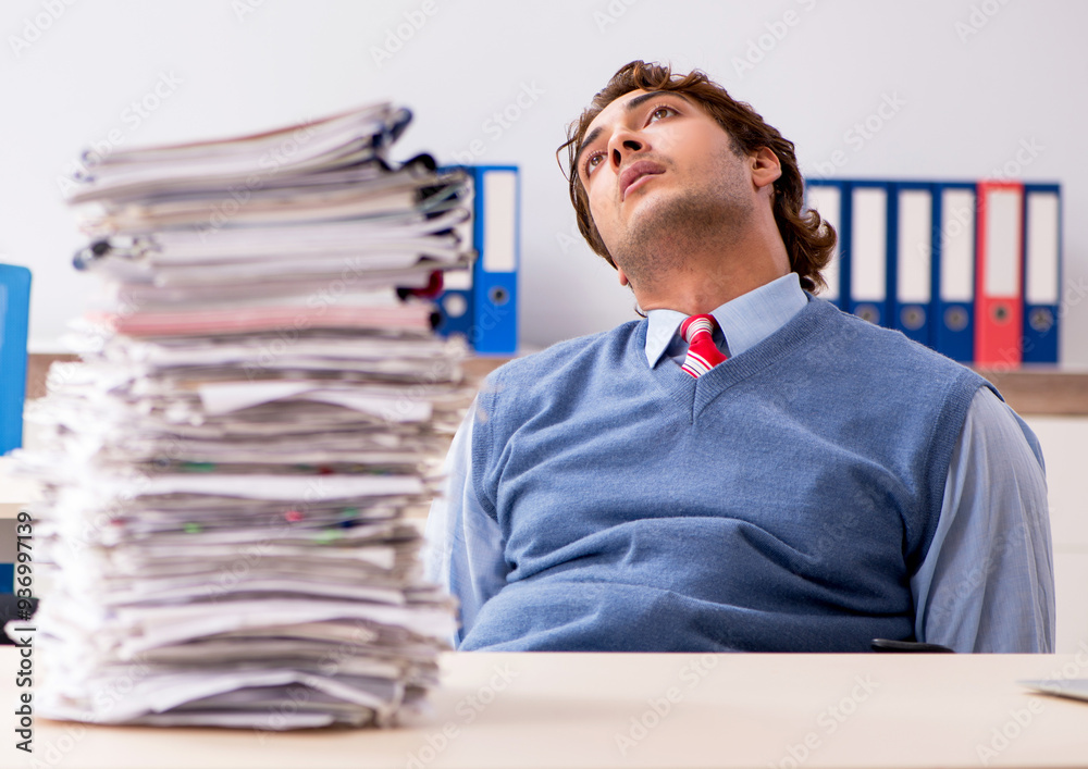 Young handsome employee unhappy with excessive work Young handsome employee unhappy with excessive work
