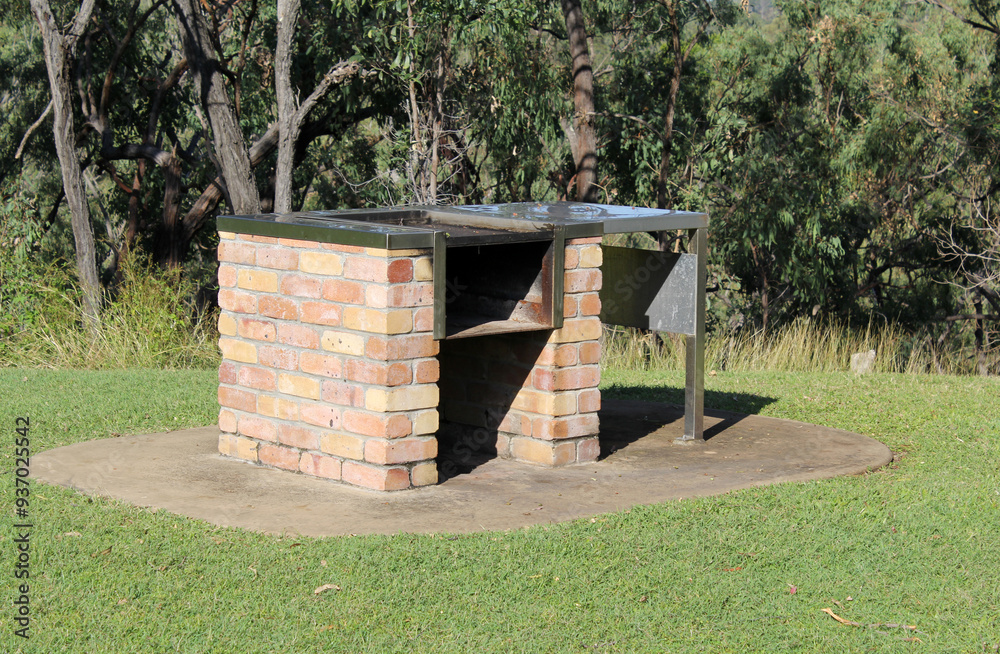 Fototapeta premium Outdoor brick barbecue grill in a park surrounded by grass and trees
