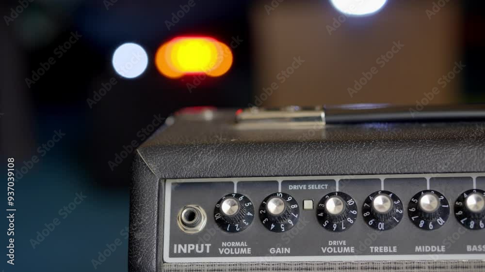 Close up of an electric guitar amplifier on a concert stage, with lights bokehing in the background. Close up of an electric guitar amplifier on a concert stage, with lights bokehing in the background.