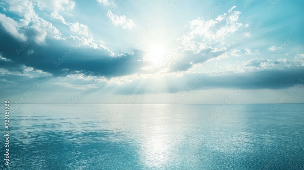 Obraz premium Sunlight breaking through clouds over a calm sea in the morning, leaving space for copy.