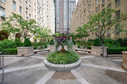 This elegant urban courtyard in New York City features meticulously landscaped gardens surrounded by classic brick buildings. The lush greenery and peaceful setting create a serene retreat amidst the 
