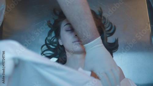 Directly above a female corpse on the table and mortician doing his job