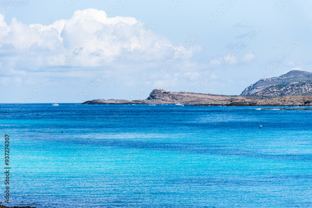 Naklejka premium A tranquil blue bay stretches towards the horizon, where Isola Piana rises gently from the sea. Set opposite the famed La Pelosa beach.