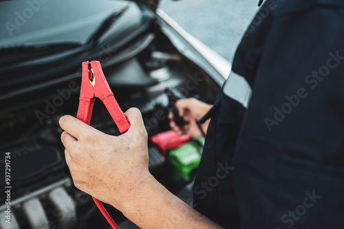 Hand car mechanic holding car booster cables for jump start car for empty battery dead and low voltage power problem or fix and service maintenance accident assistance engine doesn't start. photo