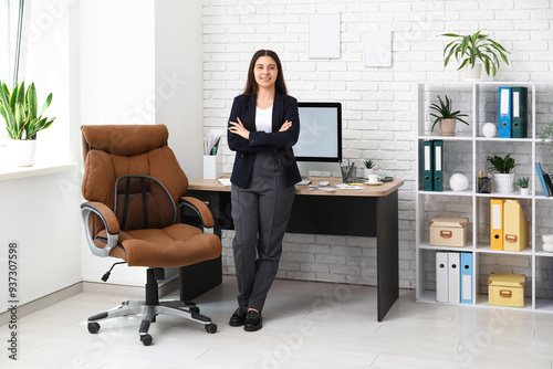 Female office worker near workplace in light office