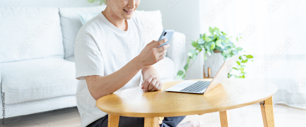自宅のリビングで携帯を見る爽やかな男性 自宅のリビングで携帯を見る爽やかな男性