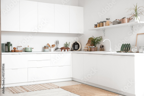 Interior of kitchen with white counters, shelf and utensils