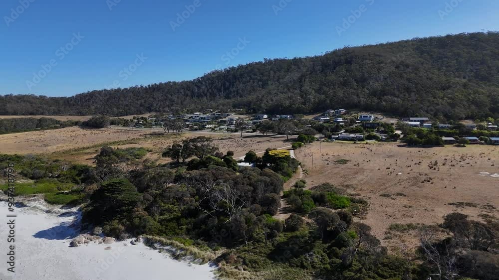 Aerial view of small Bicheno Town in Tasmania during sunny day in summer. Sandy beach and fields in foreground. Wide shot. Aerial view of small Bicheno Town in Tasmania during sunny day in summer. Sandy beach and fields in foreground. Wide shot.