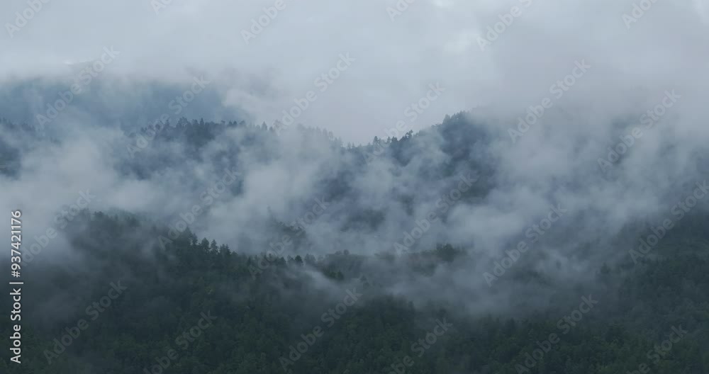 Drone shot of misty clouds flowing freely over the hills of Nepal in the evening after the monsoon rain season. The scene features a cold, lonely atmosphere with a filmy, serene scenario. Drone shot of misty clouds flowing freely over the hills of Nepal in the evening after the monsoon rain season. The scene features a cold, lonely atmosphere with a filmy, serene scenario.