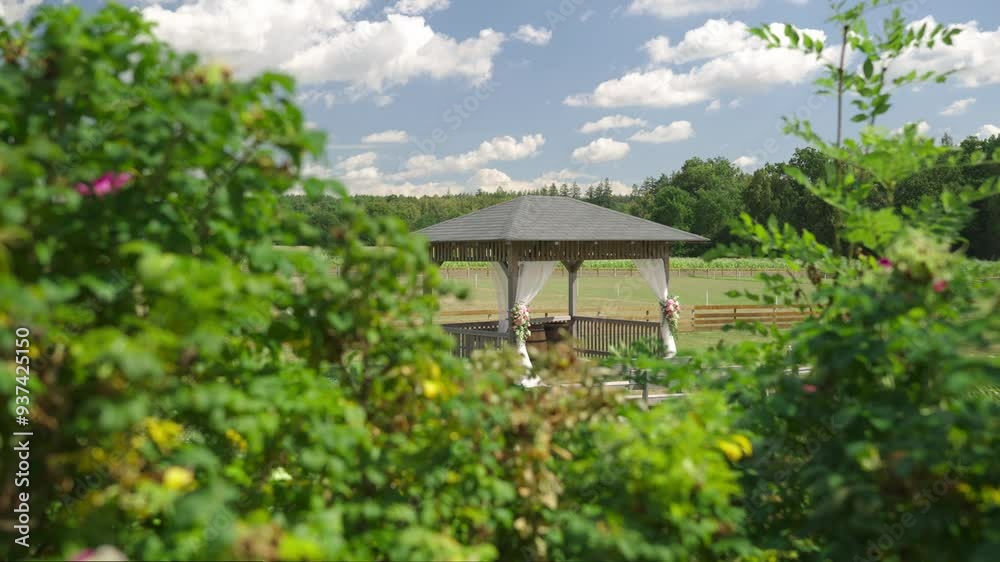 Wedding altar set up in a gazebo outdoors on a farm, beautifully decorated with flowers as preparations for the ceremony are underway.