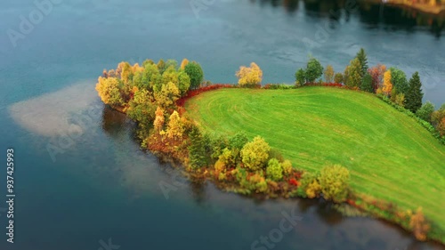 Aerial view of the small green islet with freshly cut grass on the calm slow river. Autumn forest on the river banks. Tilt-shift. photo