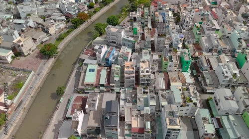 Ho Chi Min City, Vietnam District eight from top down aerial view featuring canal, bridge, rooftops, dense urban housing, streets and alleyways. Camera tracks sideways. photo