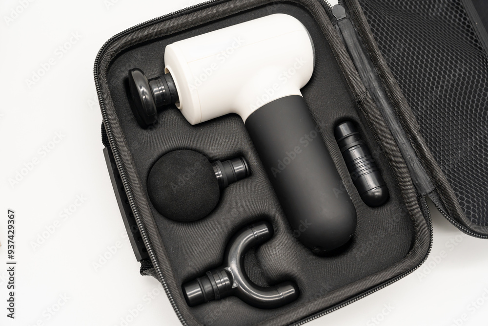 Modern massage gun for therapeutic muscle relaxation. percussion massager in the bag with accessories.
