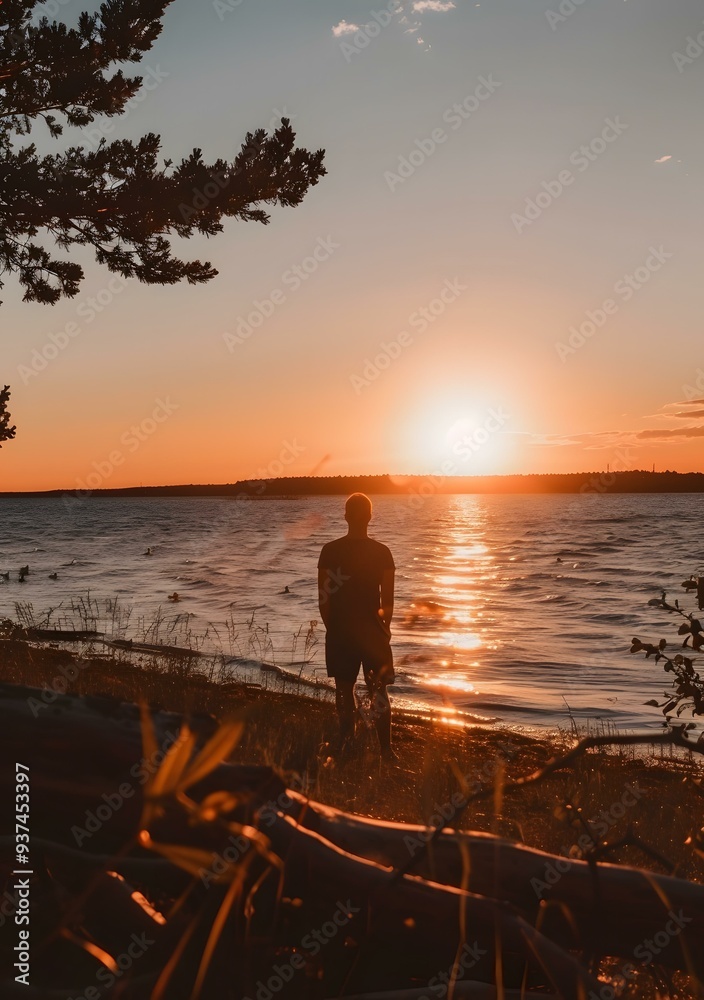 Fototapeta premium Silhouette of a Man Standing at the Beach During Sunset