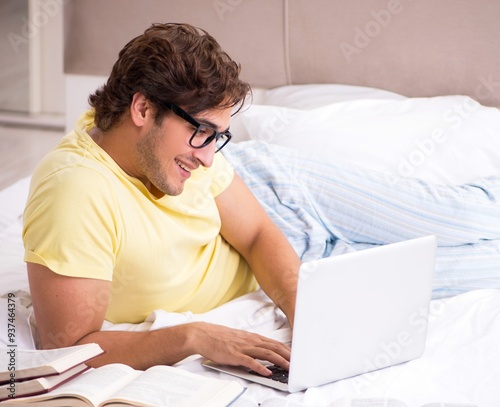 Young student studying in bed for exams