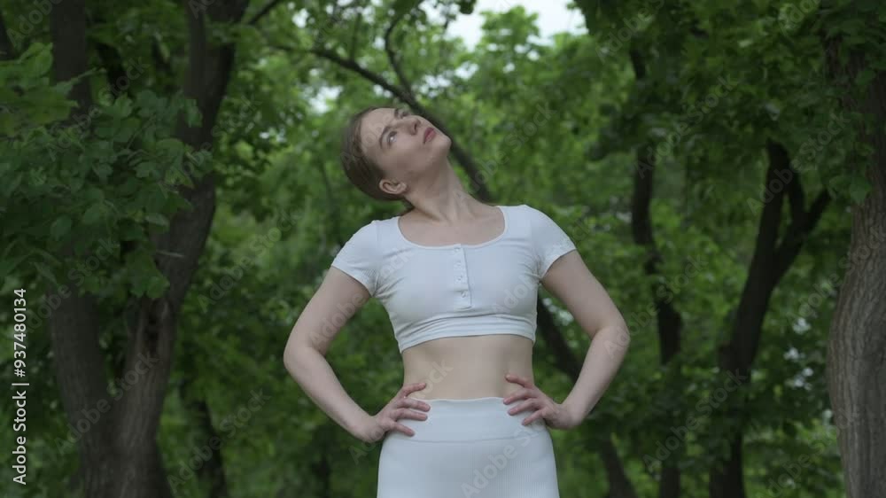Young caucasian woman in white sportswear exercising in green forest park. Outdoor workout Young caucasian woman in white sportswear exercising in green forest park. Outdoor workout