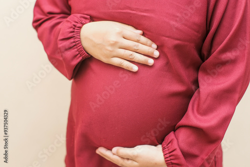Wallpaper Mural Pregnant woman in dress holds hands on belly on a cream background. Pregnancy, maternity, preparation and expectation concept. Close-up, copy space, indoors. Beautiful tender mood photo of pregnancy. Torontodigital.ca