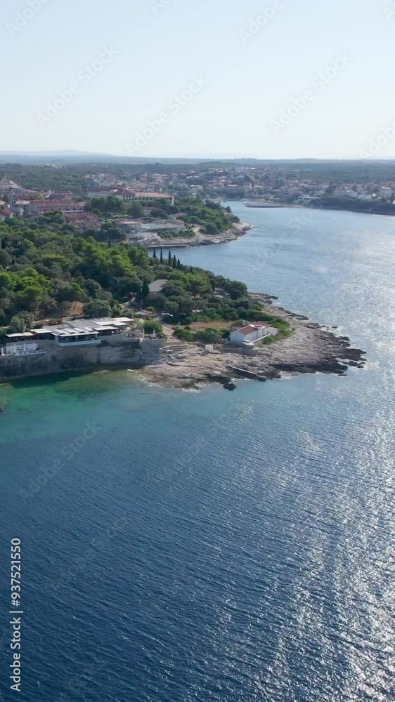 A stunning vertical (reel)view captured by drone along the shores of the Mediterranean Sea. The beautiful Croatian coast during a summer vacation, with boats and yachts slicing through the sea waters. A stunning vertical (reel)view captured by drone along the shores of the Mediterranean Sea. The beautiful Croatian coast during a summer vacation, with boats and yachts slicing through the sea waters.