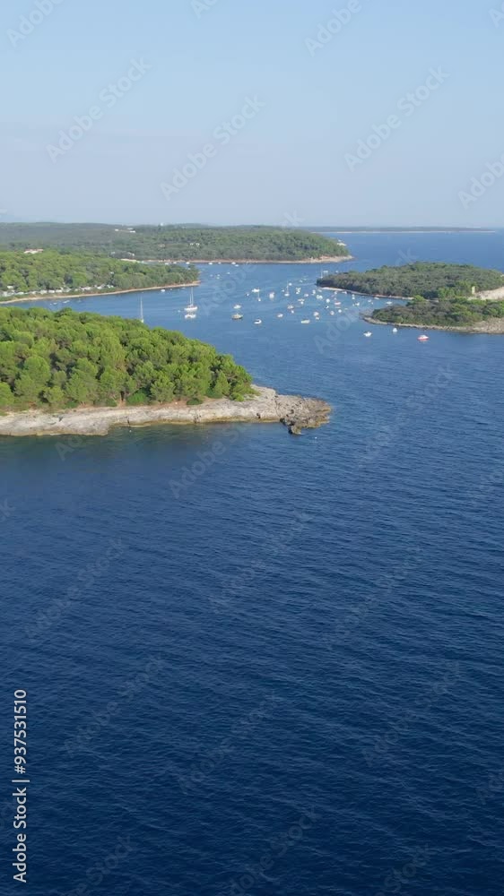 A stunning vertical (reel)view captured by drone along the shores of the Mediterranean Sea. The beautiful Croatian coast during a summer vacation, with boats and yachts slicing through the sea waters.