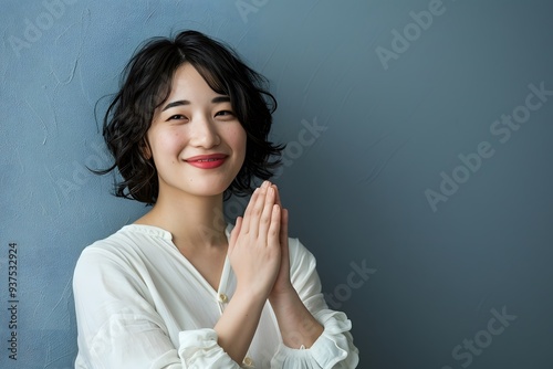 Hopeful Woman in White Blouse with Hands Together, Sitting Indoors