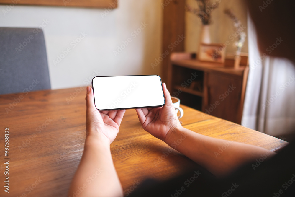 Mockup image of a woman holding and using mobile phone with blank desktop white screen at home Mockup image of a woman holding and using mobile phone with blank desktop white screen at home