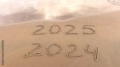 The concept of the New Year. Happy New Year 2025. Drawing, inscription, numbers 2024, 2025 in the sand. Seashore, waves, sand. Let's celebrate the new year.