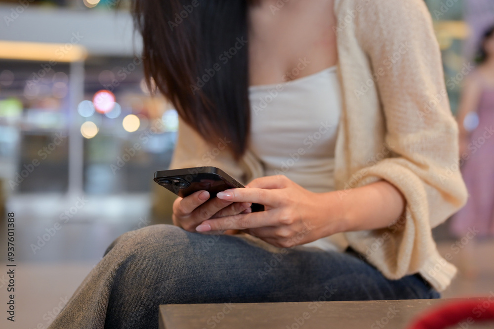 Cropped shot trendy young woman using mobile phone in in department store. People and lifestyle concept Cropped shot trendy young woman using mobile phone in in department store. People and lifestyle concept