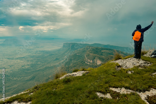 Rear view of of a hiker at the Summit of Mount Napak with Mount Kadam at the background in Karamoja, Uganda 