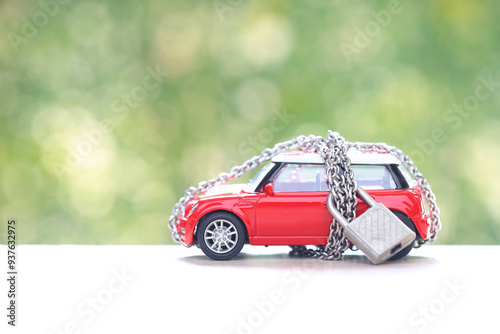 Debt,Locked miniature yellow car model with padlock and chain on natural green background,Vehicle security and Finance and car loan concept.
