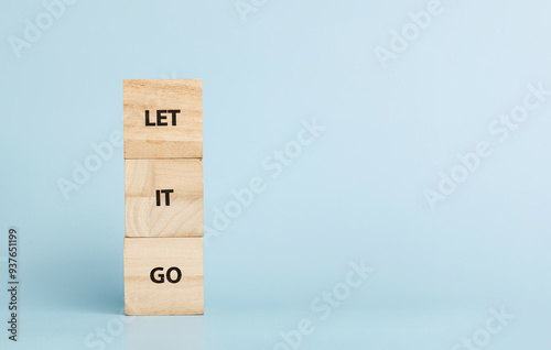 Fotografie Wooden cubes with inscriptions Let It Go on a blue background