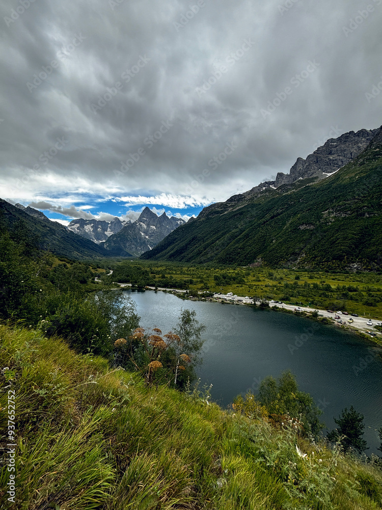 Green mountainious scenery in North Caucasus with alpine lake, beautiful meadows and dramatic sky. Green mountainious scenery in North Caucasus with alpine lake, beautiful meadows and dramatic sky.