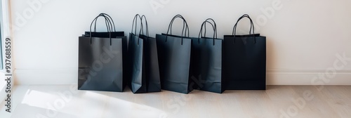 five black shopping bags lined up against a wall