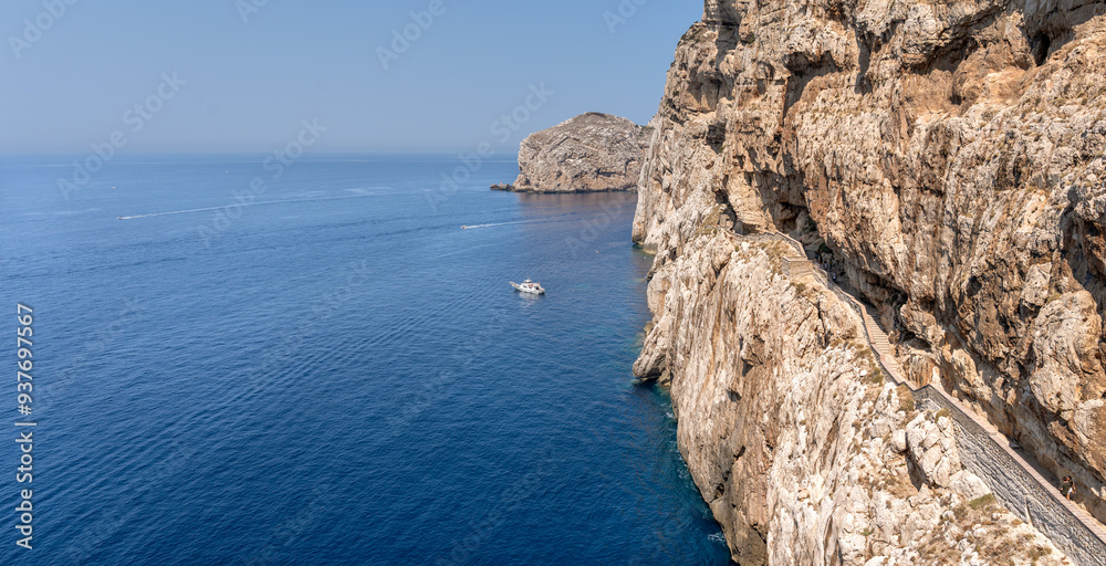 Spectacular seascape of the great cliff with access to the Neptune's Grotto (Grotta di Nettuno) dug in the middle of the cliff in Sardinia, overlooking the deep blue of the Mediterranean Sea Spectacular seascape of the great cliff with access to the Neptune's Grotto (Grotta di Nettuno) dug in the middle of the cliff in Sardinia, overlooking the deep blue of the Mediterranean Sea