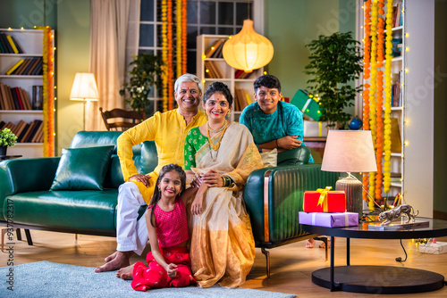 Indian family siutting with gift box on sofa on diwali festival night photo