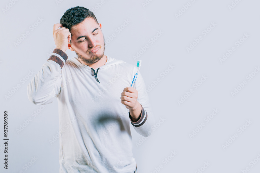 Worried young man holding toothbrush isolated. Thoughtful guy holding and looking at toothbrush isolated Worried young man holding toothbrush isolated. Thoughtful guy holding and looking at toothbrush isolated