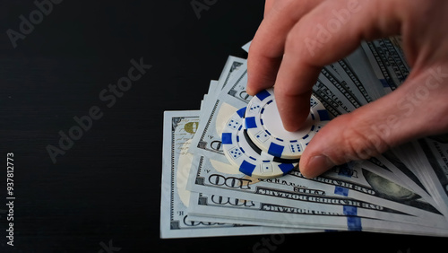 Confident places chips on stack of dollars bills. Man raises the bets in a casino gambling game. Concept of playing in a casino, poker, all-in, maximum bet