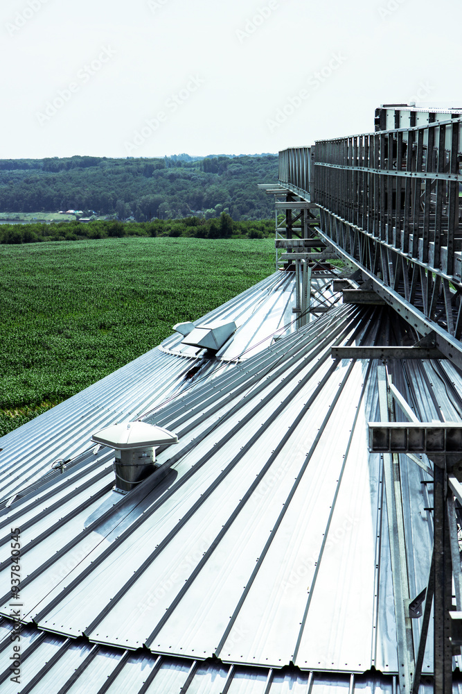 Close-up of large grain storage silos with precision-engineered metal roofs. Essential for high-capacity agricultural storage facilities. Vertical photo