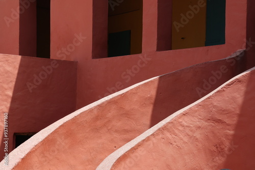 Vue d'un détail de l'escalier de couleur orangée de la maison des esclaves de l'île de Gorée au Sénégal. Rampe de forme incurvée. Architecture coloniale. Bâtiment rénové et coloré. Avril 2024.