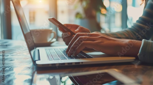 Woman's hands typing on a laptop and using a smartphone.