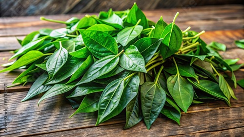 Fresh green leaves of Daun Pecah Beling, a traditional herbal plant, spread out on a wooden table, ready to be used for natural health remedies. photo