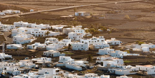 White buildings, town among volcanic black mountains and lava formations in Lanzarote, Canary Islands.