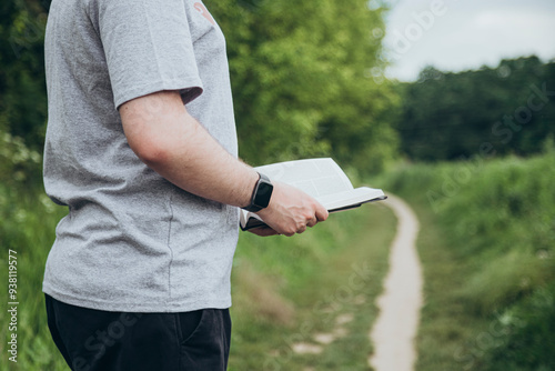 Bilde på lerret Man is holding the holy Bible outside on a blurred green background
