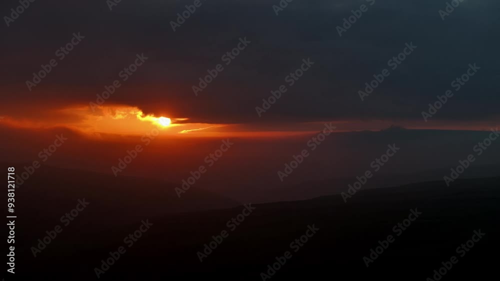 An intriguing sunrise spills orange, megenta and red hues across a moody sky over the hillsa and valleys around Arncliffe in the Yorkshire Dales √