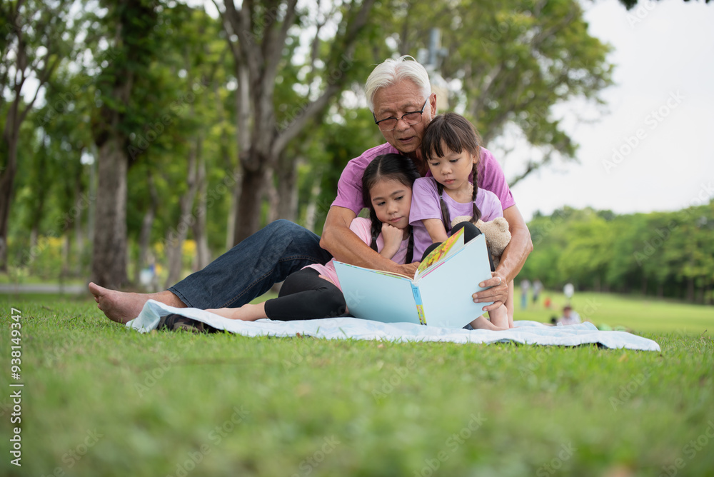 Happy Asian family children reading a book with her grandfather