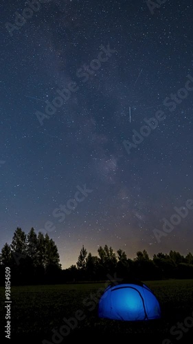 Time Lapse of Milky Way Moving over blue Glowing Tent. Night Starry Sky 