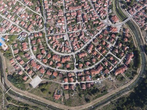 Fototapeta Naklejka Na Ścianę i Meble -  A small rural estate by the river with winding streets from above, drone shot