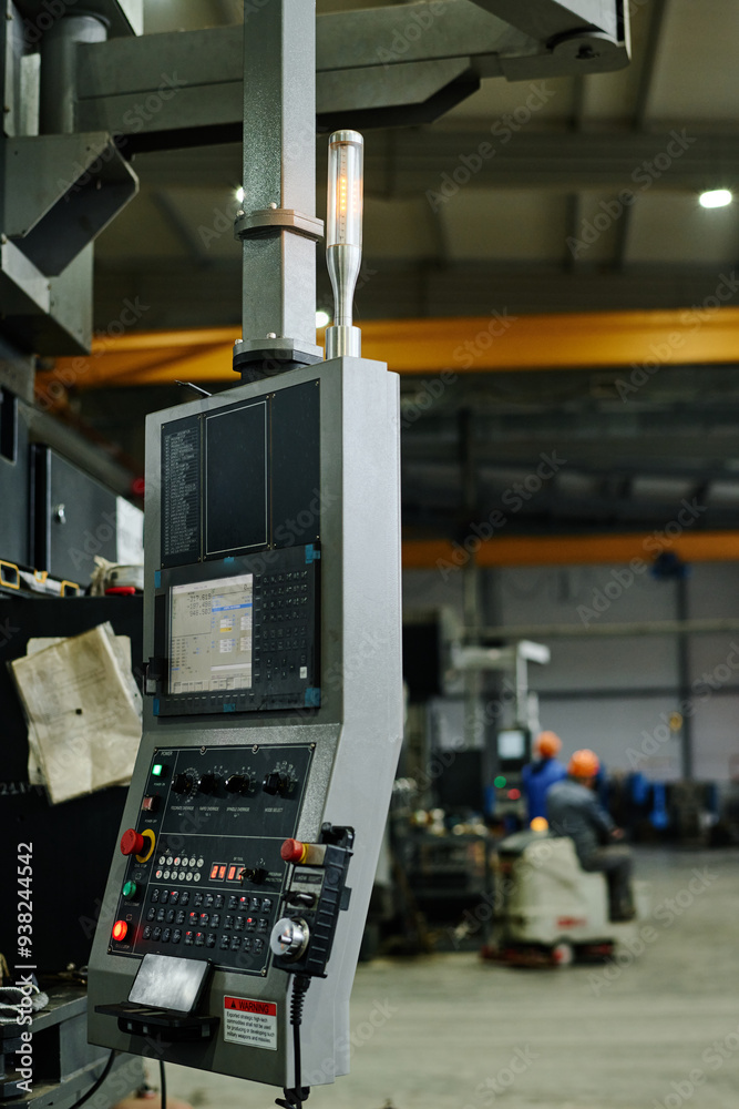 Industrial machine equipped with control panel operating in spacious factory with workers in background wearing helmets creating a secure atmosphere Industrial machine equipped with control panel operating in spacious factory with workers in background wearing helmets creating a secure atmosphere